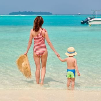 Three year old toddler boy on beach with mother. Summer family vacation at Maldives.