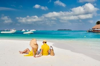 Couple in yellow on tropical beach. Summer vacation at Maldives.
