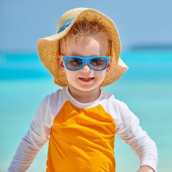 Three year old toddler boy with sunglasses on beach. Summer family vacation at Maldives.