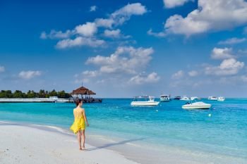 Woman in dress walking on tropical beach. Summer vacation at Maldives.