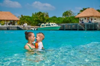 Three year old toddler boy on beach eskimo kissing his mother. Summer family vacation at Maldives.
