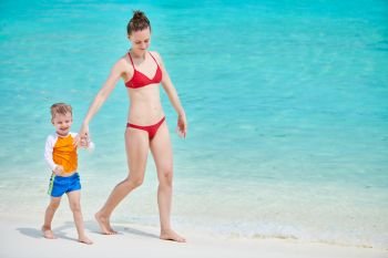 Three year old toddler boy walking on beach with mother. Summer family vacation at Maldives.