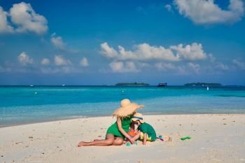 Family on beach, woman in green dress with three year old boy. Summer vacation at Maldives.