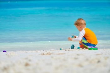 Three year old toddler boy playing with beach toys on beach.  Summer family vacation at Maldives.