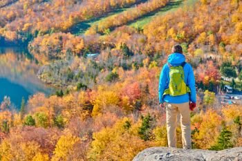 Backpacker man hiking at Artist’s Bluff in autumn. View of Echo Lake. Fall colours in Franconia Notch State Park. White Mountain National Forest, New Hampshire, USA
