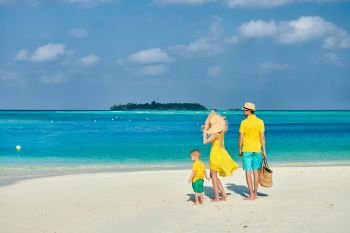 Family on beach, young couple in yellow with three year old boy. Summer vacation at Maldives.