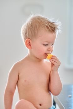 Two year old boy eating orange fruit