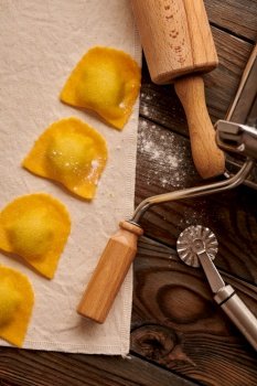 Tasty raw homemade ravioli pasta with spinach and ricotta on wooden rustic background. Process of making Italian ravioli. 