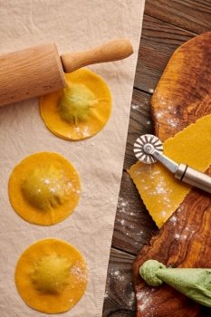 Tasty raw homemade ravioli pasta with spinach and ricotta on wooden rustic background. Process of making Italian ravioli. 