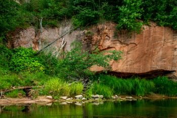 Closeup of sandstone cliff formation with cave on bank of river Gauja in Latvia. The Gauja is the longest river in Latvia, which is located only in the territory of Latvia. 