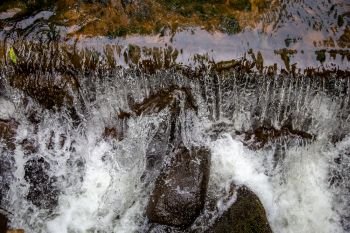 Close up of a fresh clean waterfall in forest, Latvia. Shallow stones stream with running water in spring. 