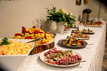 Meat dish and other snacks on the festive table in the restaurant. Various meat snacks and other appetizers on holiday table. Catering wedding table.