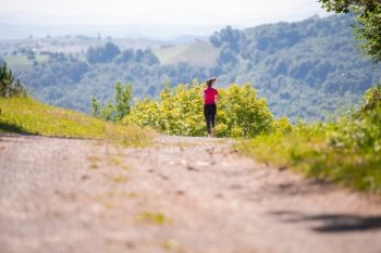 woman jogging on a country road through the beautiful sunny forest, exercise and fitness concept