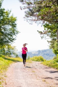 woman jogging on a country road through the beautiful sunny forest, exercise and fitness concept