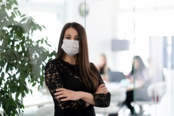 business woman portrait wearing medical mask in bright modern office new normal coronavirus outbreak concept real people