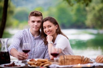 happy couple having picnic french dinner party outdoor during summer holiday vacation  near the river at beautiful nature