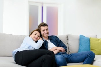 Relaxed young couple watching tv at home in bright living room
