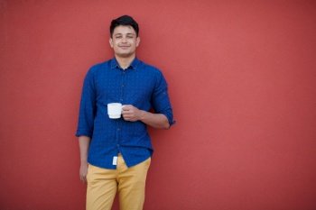 startup business  portrait of casual indian businessman with a blue shirt during coffee break from work in front of pink wall