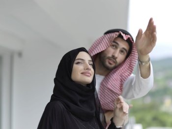 Portrait of young muslim couple on balcony. Married arabians in traditional clothes posing outdoor