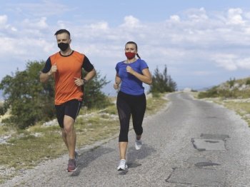 Couple running in nature at morning wearing protective face masks