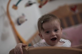 cute  little one year old baby playing with toys in bed while making first steps and learnig to walk