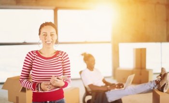 young happy casual modern muslim business woman using tablet computer on construction site with sunlight through the windows and african american colleague behind her during moving in at new startup office building