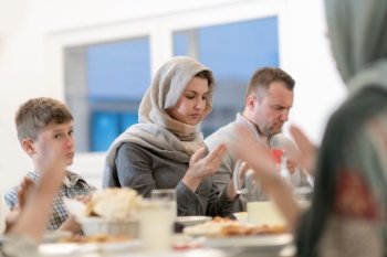 modern muslim family praying before having iftar dinner together during a ramadan feast at home