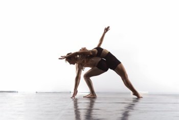 couple of young athletic dance partners in black tights performing modern style ballet making acrobatic elements  Couple of sporty ballet dancers in art performance in front of white background