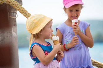 adorable little girls eating ice cream on beach by the sea during Summer vacation