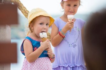 adorable little girls eating ice cream on beach by the sea during Summer vacation