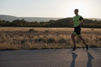 triathlon athlete running  on morning training sunrise in the background