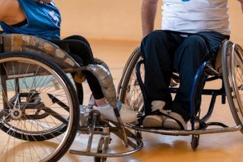 Close up photo of wheelchairs and handicapped war veterans playing basketball on the court. High quality photo. Close up photo of wheelchairs and handicapped war veterans playing basketball on the court