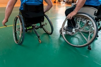 Close up photo of wheelchairs and handicapped war veterans playing basketball on the court. Selective focus . Close up photo of wheelchairs and handicapped war veterans playing basketball on the court