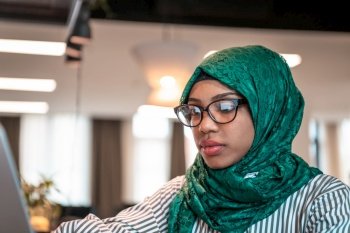 Businesswoman wearing a green hijab using laptop in relaxation area at modern open plan startup office. Selective focus. High-quality photo. Business woman wearing a green hijab using laptop in relaxation area at modern open plan startup office. Selective focus 