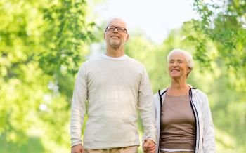 old age and people concept - happy senior couple holding hands over green natural background. happy senior couple over green natural background