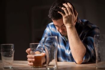 alcoholism, alcohol addiction and people concept - male alcoholic drinking beer from glass at night. alcoholic drinking beer from glass at night
