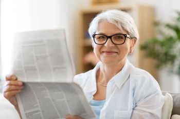 age and people concept - portrait of happy senior woman reading newspaper at home. portrait of senior woman reading newspaper at home