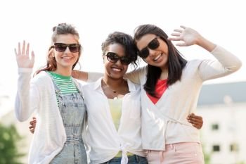 female friendship, summer and eyewear - happy young women in sunglasses outdoors waving hands. happy young women in sunglasses outdoors