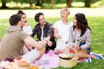friendship and leisure concept - group of happy friends with non alcoholic drinks and food at picnic in summer park. happy friends with drinks at summer picnic