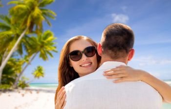 travel, tourism and summer vacation concept - happy couple hugging over tropical beach background in french polynesia. happy couple hugging over tropical beach