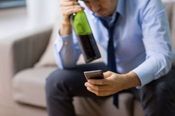 alcoholism, alcohol addiction and people concept - close up of drunk man with smartphone and bottle of wine at home. man with smartphone and bottle of alcohol at home
