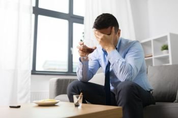 alcoholism, alcohol addiction and people concept - male alcoholic drinking brandy at home. male alcoholic drinking alcohol at home