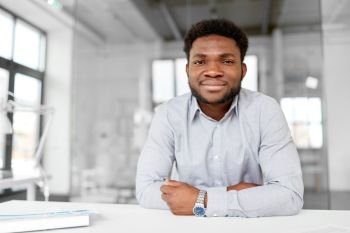 business and people concept - smiling african american businessman at office. smiling african american businessman at office