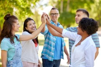 success, friendship and international concept - group of happy smiling friends making high five in park. happy friends making high five in park