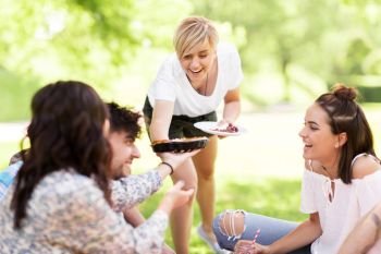 friendship, leisure and food concept - group of happy friends sharing pie at picnic in summer park. happy friends sharing pie at picnic in summer park