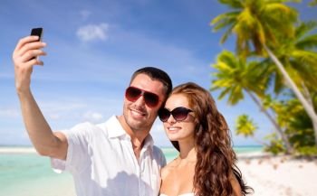 travel, tourism and summer vacation concept - smiling couple in sunglasses making selfie by smartphone over tropical beach background in french polynesia. couple making selfie by smartphone over beach