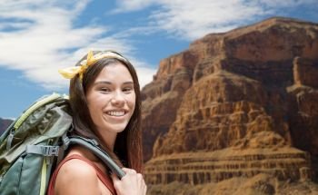 adventure, travel, tourism, hike and people concept - smiling young woman with backpack over grand canyon national park background. happy woman with backpack over grand canyon