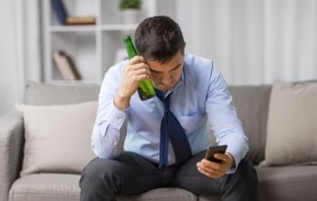 alcoholism, alcohol addiction and people concept - drunk man with smartphone and bottle of beer at home. man with smartphone and bottle of beer at home