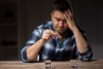 alcoholism, alcohol addiction and people concept - male alcoholic drinking shot at night. man drinking alcohol at night