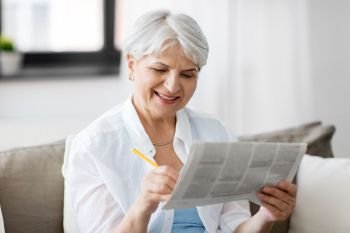 age and people concept - senior woman marking newspaper ad at home. senior woman marking newspaper ad at home